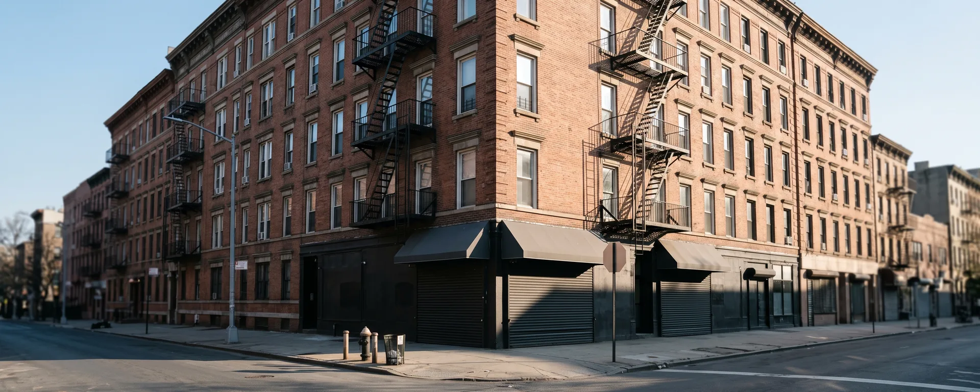 A six-story prewar walk-up with ground-floor commercial space on a Manhattan avenue corner in early morning light, the kind of income-producing building that files an RPIE every June.