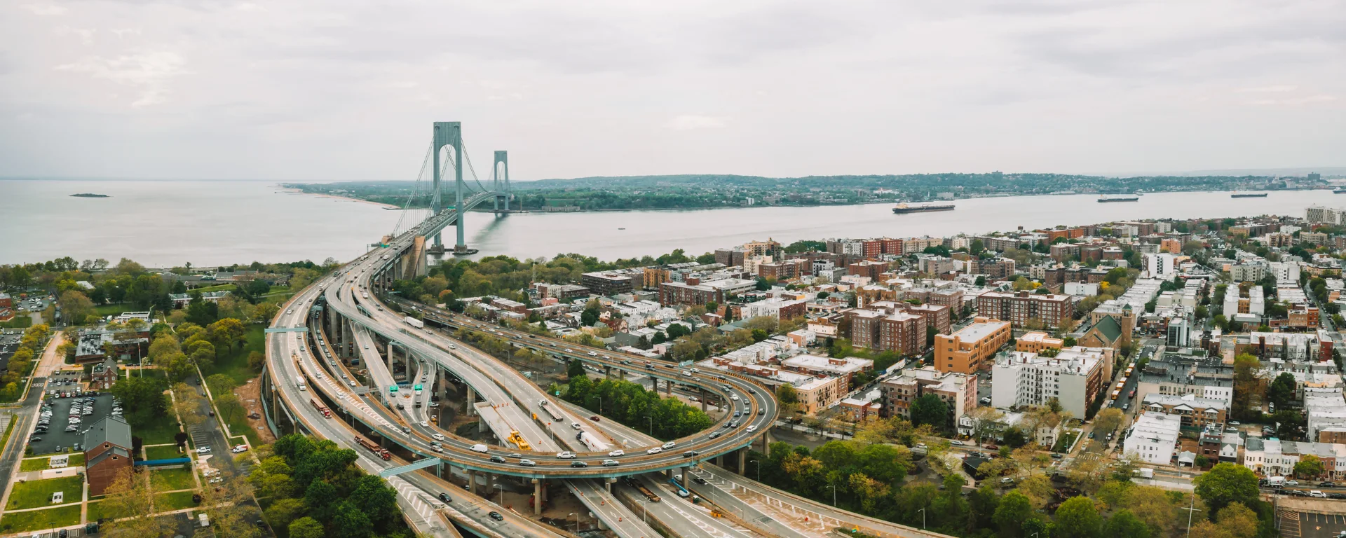 The Verrazzano-Narrows Bridge over the Narrows, with the expressway approach and rowhouse blocks below.